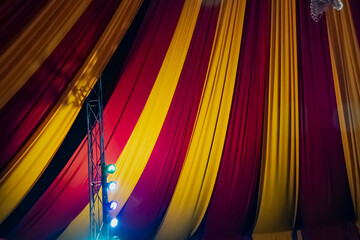 Ceiling decorated with heavy fabrics and light bulbs to show a circus feeling. Colorful curtain and...