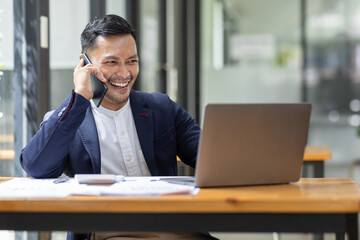 Fototapeta premium Professional young asian business man using computer laptop and Talking On Phone and work On Laptop in the workplace Modern Office.