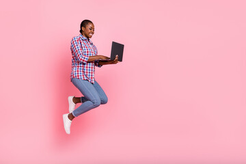 Full body profile photo of attractive energetic lady jump hold netbook empty space isolated on pink color background