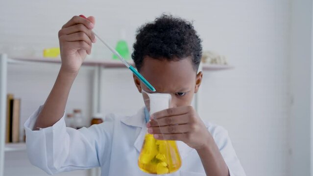 4K, Asian mixed-race boy is interested in liquid in science lab jug when dry ice is added to cause steam to gush out in elementary school's science classroom. Concept education, Science experiments