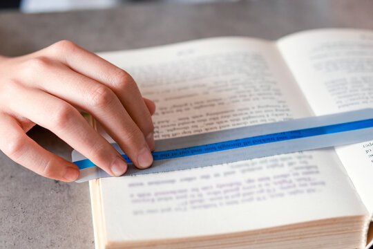 Reading tools for dyslexia. Child reading book using colorful ruler overlay strips. Education, learning disability, reading difficulties concept