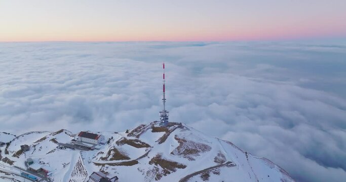 Telecommunications tower on top of Mount Rigi (Rigi Kulm) with amazing snow and fog covered Swiss alps mountain peaks and Lake Lucerne underneath in winter scenery landscape. Aerial drone. Switzerland