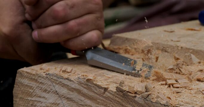 Close up detail of carpenter chiseling a wooden beam for log cabin construction in the mountains
