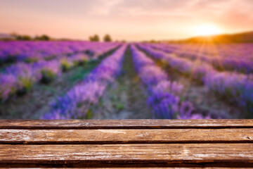 Empty wooden table in front of a blurred blooming lavender field under the golden colors of the...
