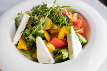 Salad with cheese and fresh vegetables on white plate. Greek salad.Food dieting concept.Fresh Greek salad - feta cheese, colorful cherry tomatoes, cucumber