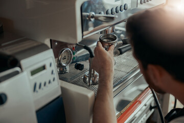 Man worker in uniform inspecting coffee machine in own workshop