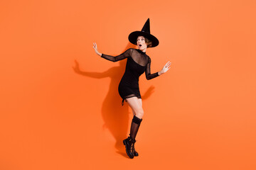 Fototapeta na wymiar Full body photo of cute girl look frighten empty space escape dressed trendy black halloween garment isolated on orange color background