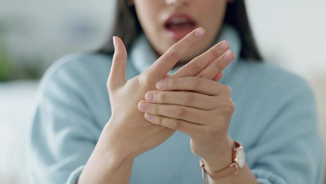 Health, hand and massage with woman suffering from pain in her hands and wrist, looking uncomfortable in a living room. Closeup on inflammation or arthritis from an injury to fingers by a female