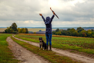 A woman walks her dog in a field after a thunderstorm. Girl with staffordshire terrier in nature on a cloudy day. The concept of freedom, happiness, friendship, nature.