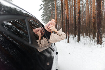Rear view of girl in car over snowy forest on winter roadtrip