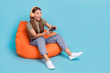Portrait of funky nice girl brown hair dressed striped t-shirt game level have fun on playstation isolated on blue color background © deagreez
