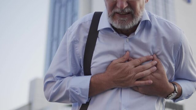 Mature man feeling pain, holding hands on chest, risk of stroke or heart attack