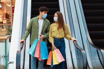 Couple Shopping Holding Bags Standing On Moving Stairs In Mall