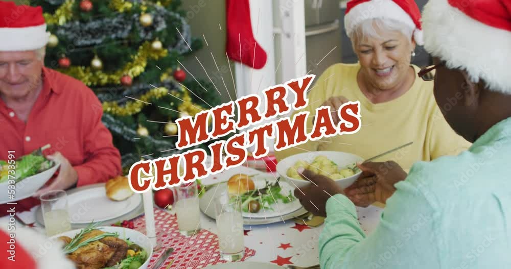 Sticker Animation of merry christmas text in red over happy diverse senior friends at christmas dinner table