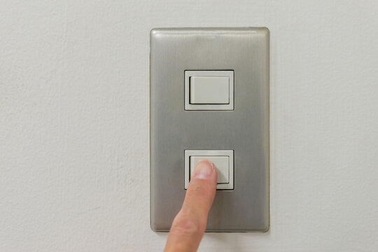 壁の電気のスイッチのボタンを人差し指で押す