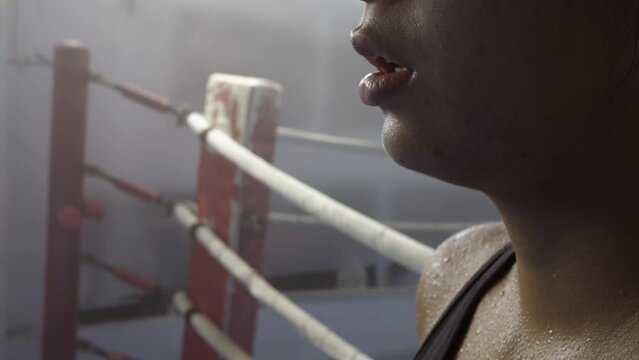 Exhausted female fighter with sweat on face after workout, close up side view. Sportswoman hard training. Endurance, determination, challenge concept