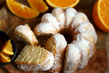 Soft and fluffy orange cake with powdered sugar on a wooden board.