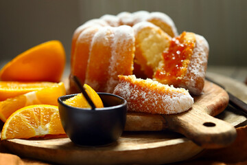 Soft and fluffy orange cake with powdered sugar on a wooden board.