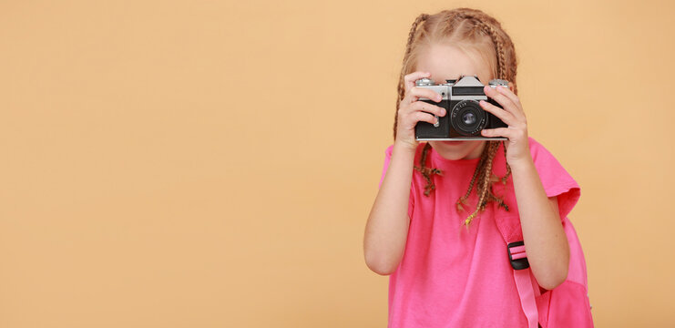 banner of adorable child girl takes picture with vintage retro camera. Little girl photographer on yellow background. Hobby for kids and happy childhood. Education and smart kid girl concept.