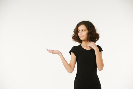 A girl in black clothes on a white background depicts the emotion