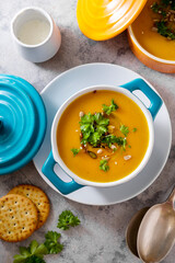 Pumpkin or butternut squash autumn creamy soup, blue bowl, grey background