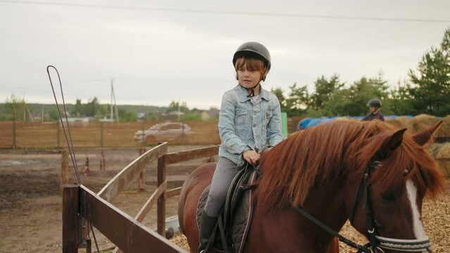 little girl is riding pony in equestrian center for children, sport classes for kids for physical development