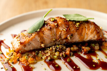 Salmon with vegetable saute. Served with fried pistachios and teriyaki sauce.