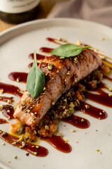 Salmon with vegetable saute. Served with fried pistachios and teriyaki sauce.