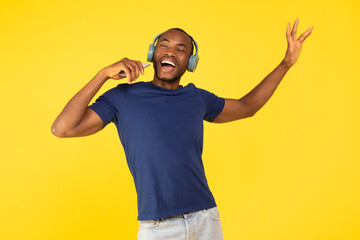 Naklejka premium Black Male Singer Singing Holding Smartphone Like Microphone, Yellow Background