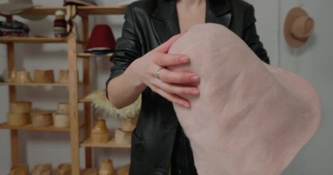 Professional milliner in leather jacket tries hard to absorb glue into hat