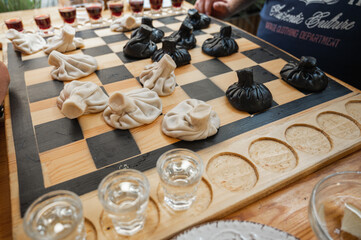 Traditional Georgian dish, khinkali Kalakuri, on wooden table, chess board, rustic, side view, black and light dough, chess game. Selective focus, side view. Meat and cheese dishes