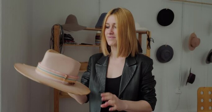Satisfied milliner puts on finished hat looking in camera