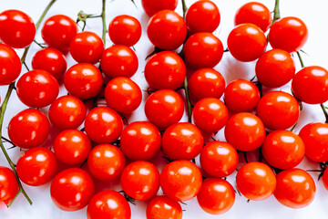 bunch of fresh red cherry tomatoes with green stems on white background.