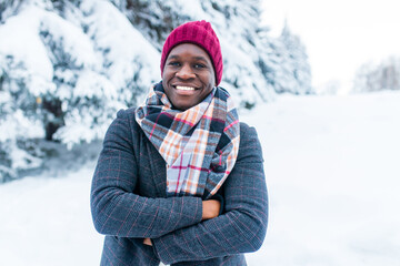 african american handsom man in red hat and stylish plaid coat look at camera with toothy snow- white smile outdoor in park