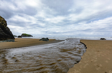 Wide landscape panoramic view of Bandon Beach, Oregon, on a moody sky, puffy cloud day.