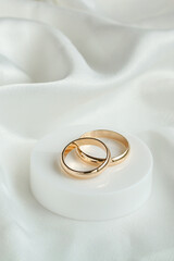 Wedding background with two gold rings on white satin material. Marriage.