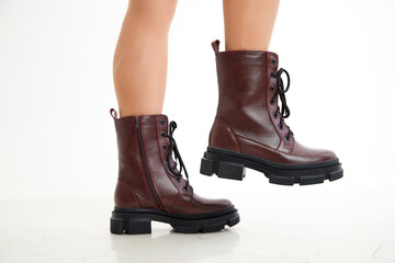 Female winter, autumn or spring brown leather shoes on leg of woman in studio on white background. Fashionable modern photography and photoshoot for a store, catalog, magazine or online