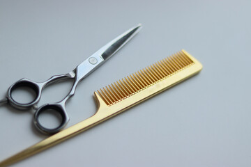 scissors and comb on white background.gold comb and silver scissors.silver scissors on white background.barber tools.hairdresser.gold scissors.