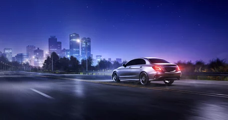Zelfklevend Fotobehang Generieke auto die & 39 s nachts rijdt op een snelweg in de voorsteden met een stadslandschap en bergen op de achtergrond. 3D-rendering © 3dartists