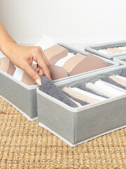 Woman puts towel in an organizer. Concept of order in house. Gray closet organizers drawer divider...