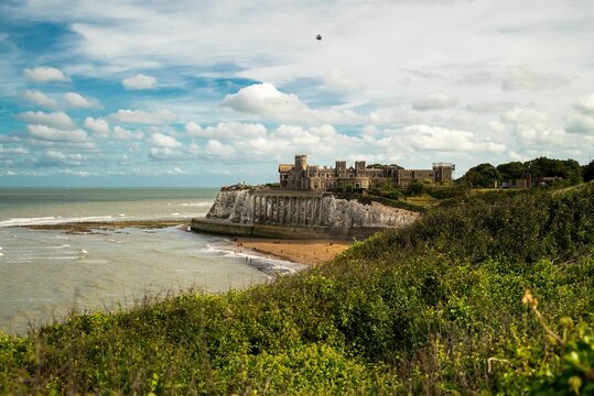 Kingsgate castle view with grass and sandy seashore view, cloudy sky background