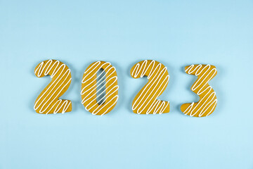 2023 number made of gingerbread cookie with white icing on blue background. Merry Christmas and Happy New Year.