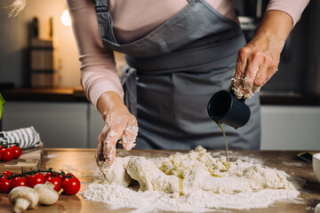 close up of woman prepares dough in her kitchen, adding oil