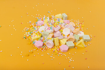 Tablet candies on yellow background. Compressed sugar powder confectionery, dextrose candy necklace parts, vitamin c tablets, lozenges pile