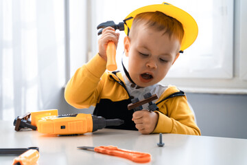 Child play with work tools at home, dreams to be an engineer. Little boy builder. Education, and imagination, purposefulness concept. Kid and hummer - 533756974