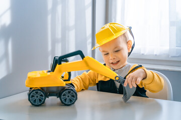 Fototapeta na wymiar Child play with excavator at home, dreams to be an engineer. Little builder. Education, and imagination, purposefulness concept. Boy with digger