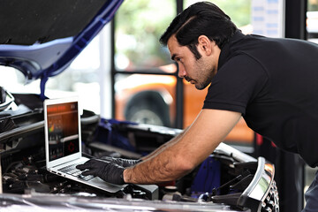 Car mechanic working with a notebook in Auto Repair Service checking car engine.