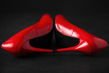 bright red shoes with high heels stilettos lie on a dark background