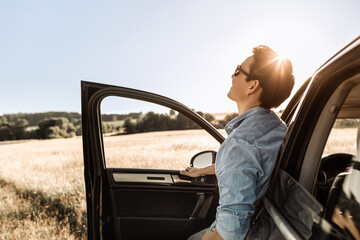 Happy young man getting out of his car looking up to the sky enjoying a beautiful nature view. Happiness and adventure  - Powered by Adobe
