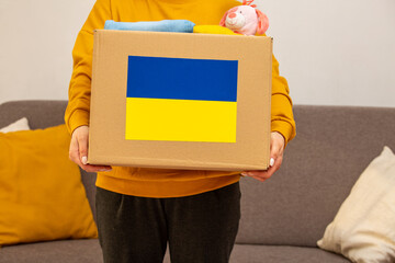 Close up box with Ukrainian flag for humanitarian aid donation with children's things and toys at...